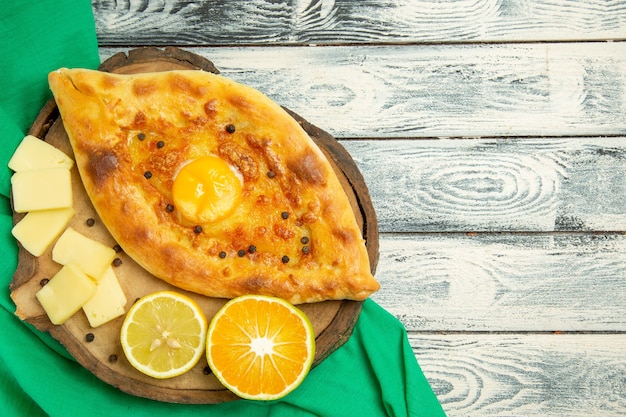 Draufsicht köstliches Eierbrot, das mit Käse auf einem rustikalen grauen Schreibtisch gebacken wird