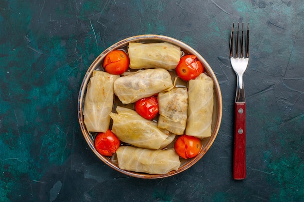 Draufsicht köstliches Fleischmehl, das in Kohl mit Tomaten und Gabel auf dunkelblauem Schreibtischfleischnahrungsmittelabendessen kaloriengemüse gekocht wird