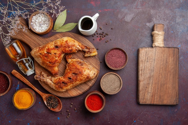 Draufsicht köstliches gebratenes Huhn mit verschiedenen Gewürzen auf dunklem Schreibtisch