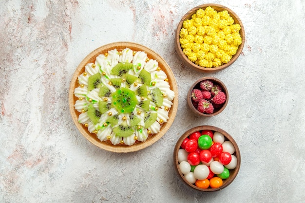 Draufsicht köstliches Kiwi-Dessert mit Bonbons auf weißem Hintergrund Dessertkuchen Sahnefrucht Tropical