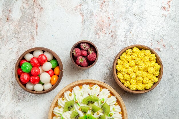 Draufsicht köstliches Kiwi-Dessert mit Bonbons auf weißem Hintergrund Dessertkuchen Sahnefruchtsüßigkeit