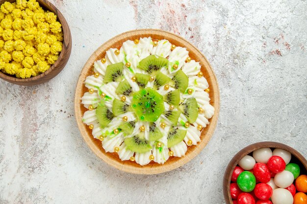 Draufsicht köstliches Kiwi-Dessert mit weißer Sahne und Bonbons auf weißem Hintergrund Dessert-Süßigkeiten-Sahne-Kuchen-Frucht