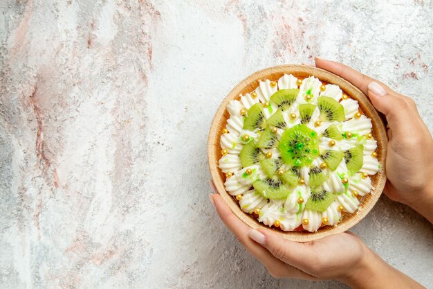 Draufsicht köstliches Kiwi-Dessert mit weißer Sahne und in Scheiben geschnittenen Kiwis auf weißem Hintergrund Dessert-Frucht-Süßigkeiten-Sahne-Torte