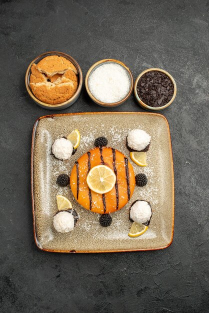 Draufsicht köstliches Kuchendessert mit Kokosbonbons auf dem dunklen Oberflächenkuchendessert süßer Kuchensüßigkeitstee