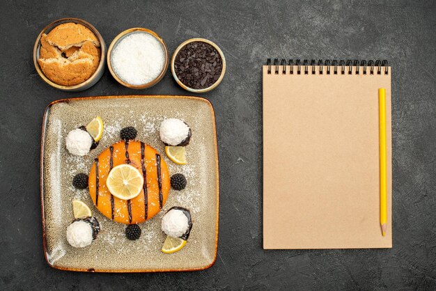 Draufsicht köstliches Kuchendessert mit Kokosbonbons auf dunklem Oberflächenkuchenkuchen-Dessert süßer Süßigkeitstee