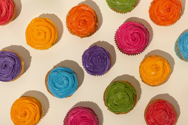 Kostenloses Foto draufsicht köstliches regenbogen-cupcake-glasur-stillleben