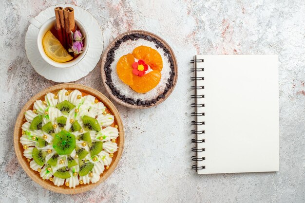 Draufsicht köstliches Sahnedessert mit Tasse Tee auf weißem Schreibtischfarbe Süßigkeitskekscremedessert