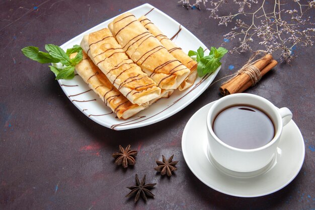 Draufsicht köstliches süßes Gebäck mit Tasse Tee auf dem dunklen Raum