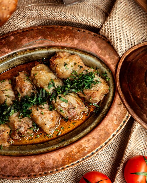 Draufsicht Kohlröllchen mit Kräutern und Tomaten auf dem Tisch