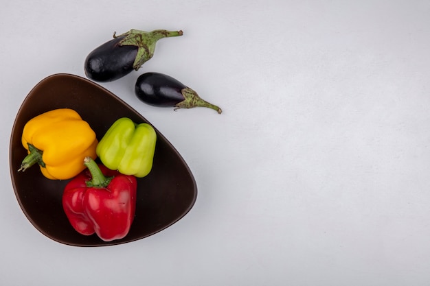 Draufsicht kopieren Raum-Aubergine mit farbigen Paprika in der Schüssel auf weißem Hintergrund