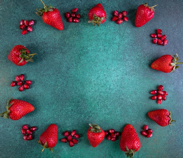 Draufsicht kopieren Raum Erdbeeren mit geschältem Granatapfel an den Rändern auf Grün