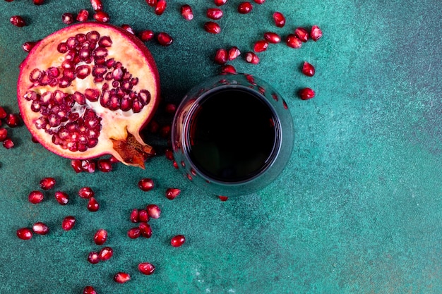 Draufsicht kopieren Raum gehackten halben Granatapfel mit einem Glas Granatapfelsaft auf einem grünen Hintergrund