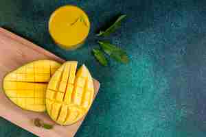 Kostenloses Foto draufsicht kopieren raum geschnittene mango auf tafel mit einem glas orangensaft und minzblättern