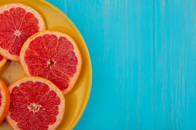 Draufsicht kopieren Raum Grapefruitkeile auf gelbem Teller auf türkisfarbenem Hintergrund