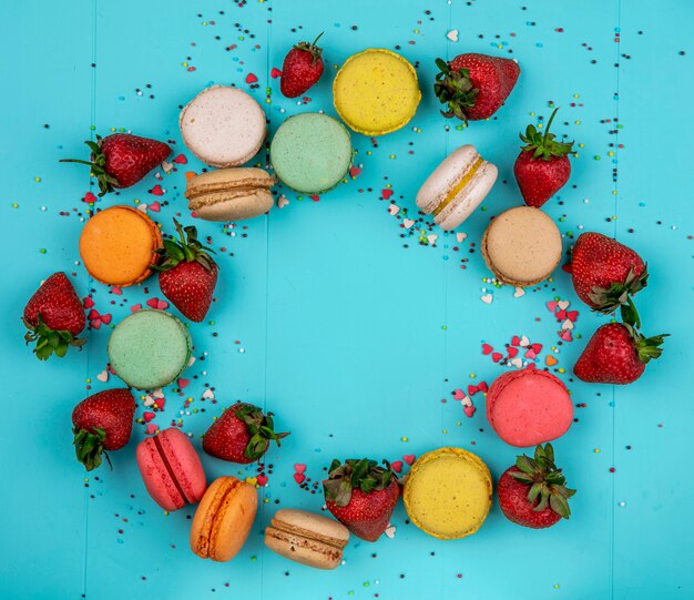 Draufsicht kopieren Raum mehrfarbige Macarons mit Erdbeeren auf einem blauen Hintergrund
