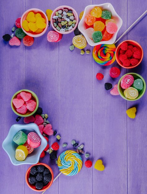 Draufsicht kopieren Raum mehrfarbige Marmelade mit Schokoladensteinen und farbigen Eiszapfen in Untertassen für Marmelade auf einem lila Hintergrund