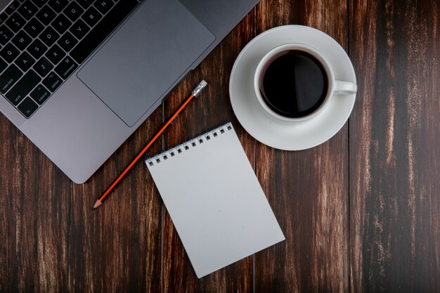 Draufsicht kopieren Raum Tasse Tee mit Notizbuchstift und Notizbuch auf hölzernem Hintergrund