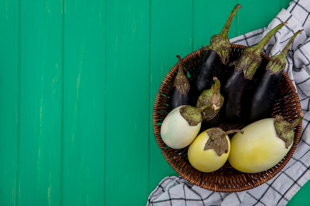 Draufsicht kopieren Raum weiße und schwarze Aubergine in einem Korb auf einem karierten Handtuch auf einem grünen Hintergrund