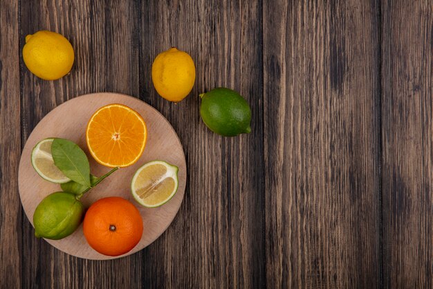 Draufsicht kopieren Raumkalkhälften mit orangefarbener Hälfte auf Ständer mit Zitronen auf hölzernem Hintergrund