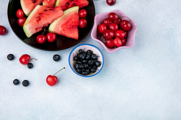 Draufsicht kopieren Raumscheiben der Wassermelone auf einem Teller mit Blaubeeren und Kirschen