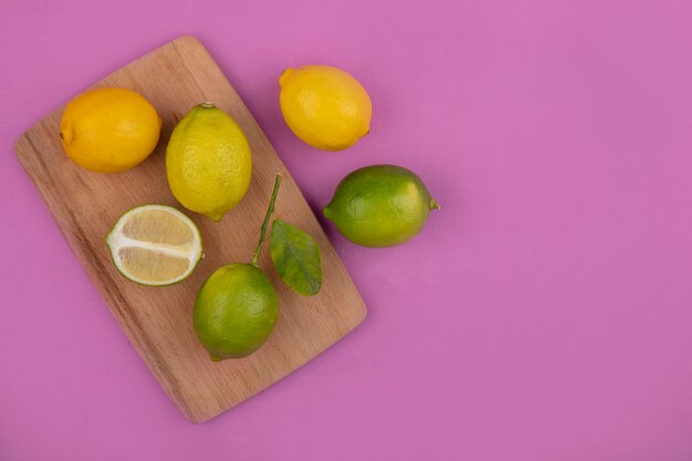 Draufsicht kopieren Raumzitronen mit Limetten auf Schneidebrett auf rosa Hintergrund