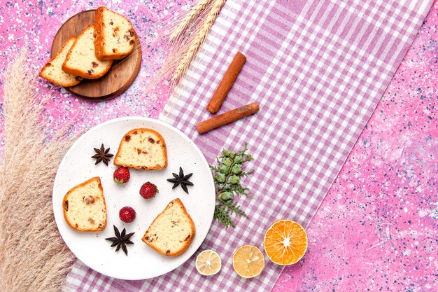 Draufsicht-Kuchenscheiben mit Erdbeeren und Zimt auf dem rosa Hintergrundkuchen backen süße Keksfarbkuchen-Zuckerkekse