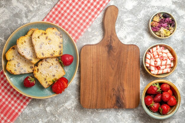 Draufsicht Kuchenscheiben mit frischen Erdbeeren auf leichter Oberfläche süße Kuchenfrucht