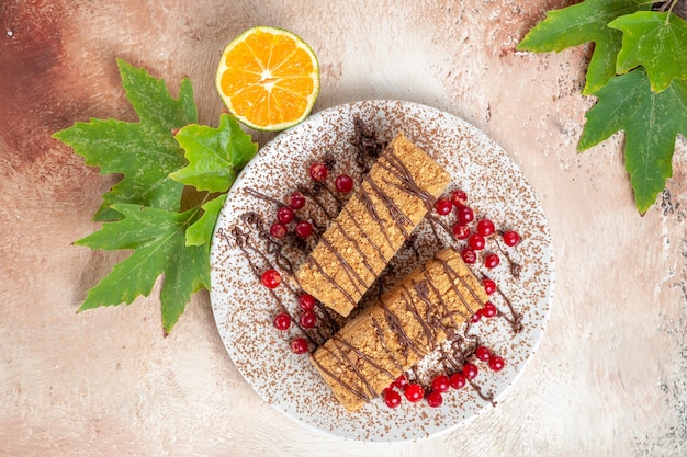 Kostenloses Foto draufsicht kuchenscheiben mit schokoglasur und roten beeren auf hellem boden kekskuchen süß