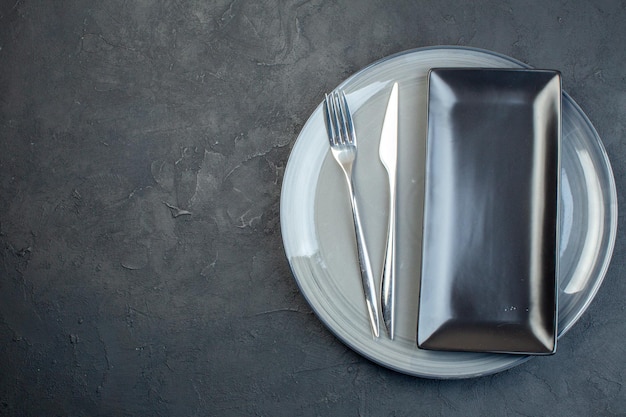 Draufsicht lange schwarze Platte mit Gabel und grauer Platte auf dunklem Hintergrund horizontale bunte Weiblichkeit Besteck Glas Essen