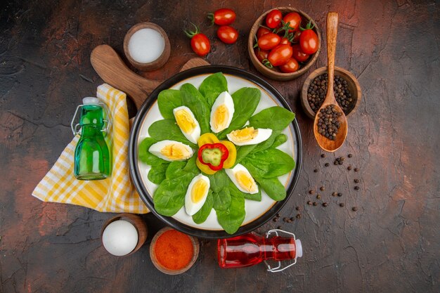 Draufsicht lecker gekochte Eier mit Gewürzen und Tomaten auf dunklem Tisch