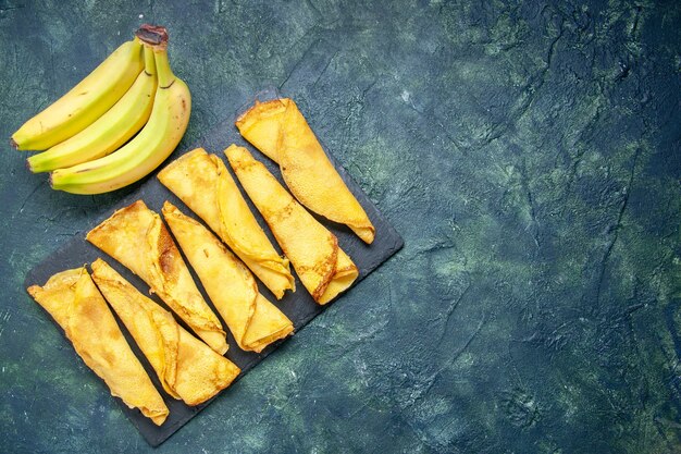 Draufsicht lecker gerollte Pfannkuchen mit Bananen auf dunklem Hintergrund Kuchenteig Hotcake Farbe Mahlzeit Gebäck süßer Kuchen Fleisch freier Raum
