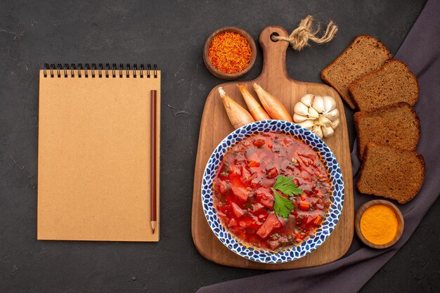 Draufsicht leckere Borschtsch ukrainische Rübensuppe mit dunklen Brotlaiben auf dem dunklen Raum