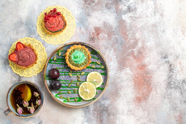 Draufsicht leckere cremige Kuchen mit Tasse Tee auf hellem Hintergrund süßer Bonbonkeks