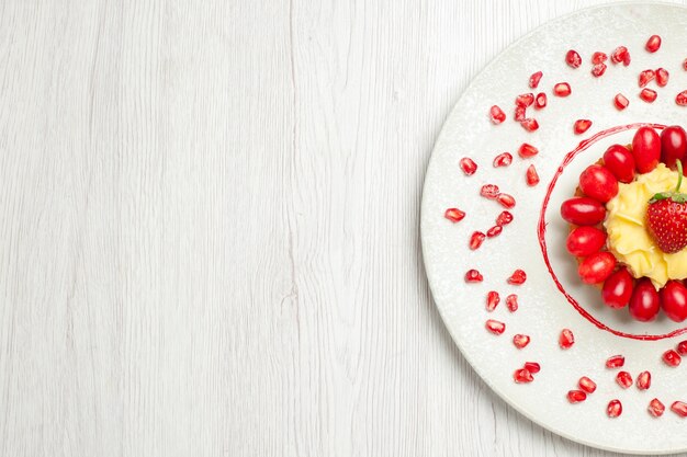 Draufsicht leckere cremige Torte mit Hartriegeln auf weißem Schreibtisch