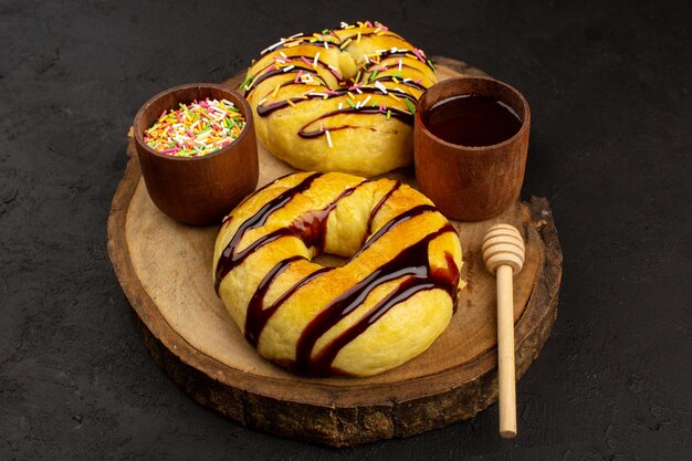 Draufsicht leckere Donuts köstlich süß mit Schokolade auf dem braunen Schreibtisch und dunklem Hintergrund