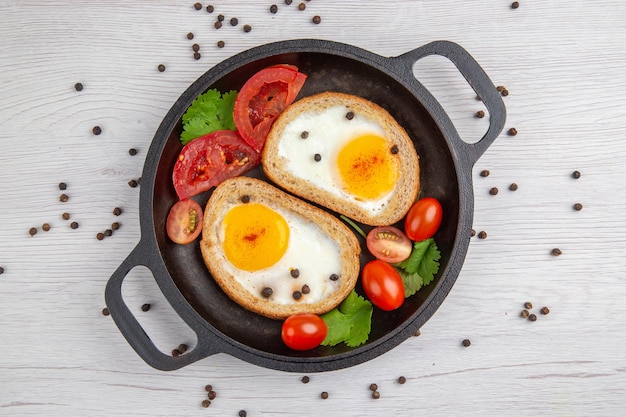 Draufsicht leckere eiertoasts mit tomaten in der pfanne auf weißem hintergrund frühstück mittagessen farbe salat essen mahlzeit