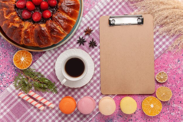 Draufsicht leckere Erdbeerkuchen mit französischen Macarons auf rosa