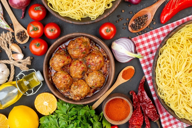 Draufsicht leckere Fleischbällchensuppe in Schüssel Spaghetti in Schüssel Ölflasche Tomaten Petersilie auf Tisch