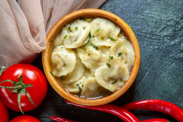 Draufsicht leckere Fleischknödel in Holzteller mit frischen Tomaten auf dunkler Oberfläche