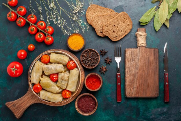 Draufsicht leckere Fleischmahlzeit in Kohl mit Brot und frischen Tomaten auf dem dunkelblauen Schreibtisch gerollt