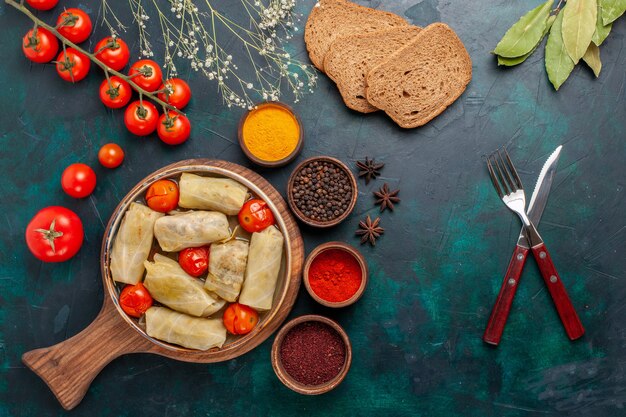 Draufsicht leckere Fleischmahlzeit in Kohl mit Brot und frischen Tomaten auf dem dunkelblauen Schreibtisch gerollt