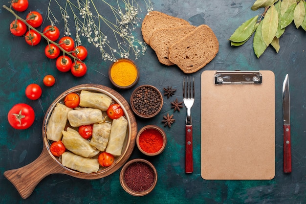 Draufsicht leckere Fleischmahlzeit in Kohl mit Brot und frischen Tomaten auf dem dunkelblauen Schreibtisch gerollt