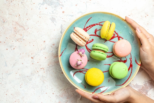 Draufsicht leckere französische Macarons innerhalb des Tellers auf weißem Kuchenkeks süß