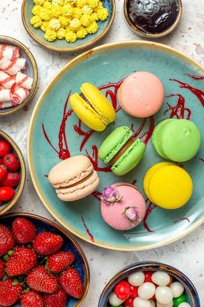 Draufsicht leckere französische macarons mit beeren und süßigkeiten auf weißem kuchen süßem keks