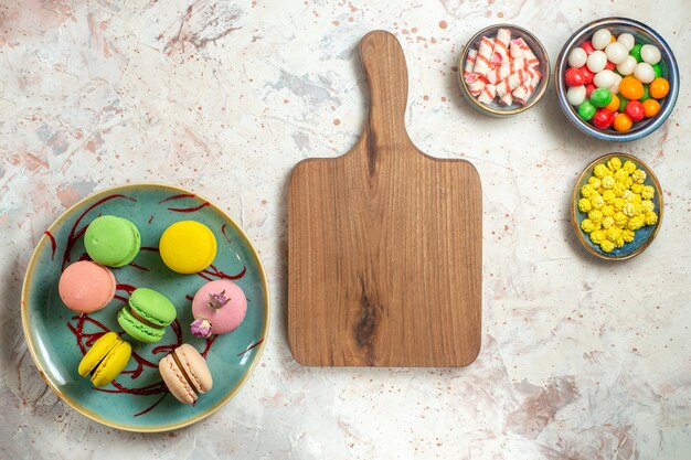 Draufsicht leckere französische Macarons mit Süßigkeiten auf weißem Kuchenkeksplätzchen