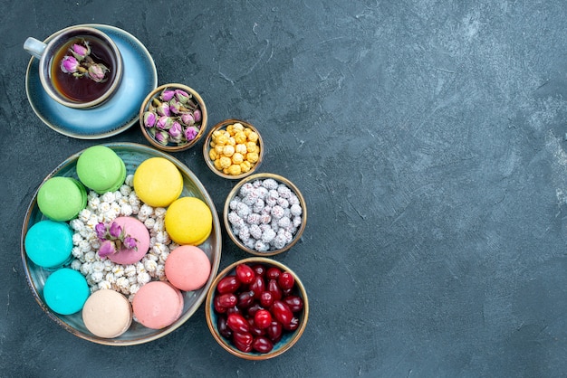 Kostenloses Foto draufsicht leckere französische macarons mit tasse tee auf dunkelheit