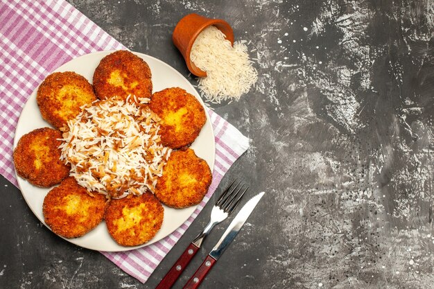 Draufsicht leckere gebratene Schnitzel mit gekochtem Reis auf der dunklen Oberfläche Frikadellengericht