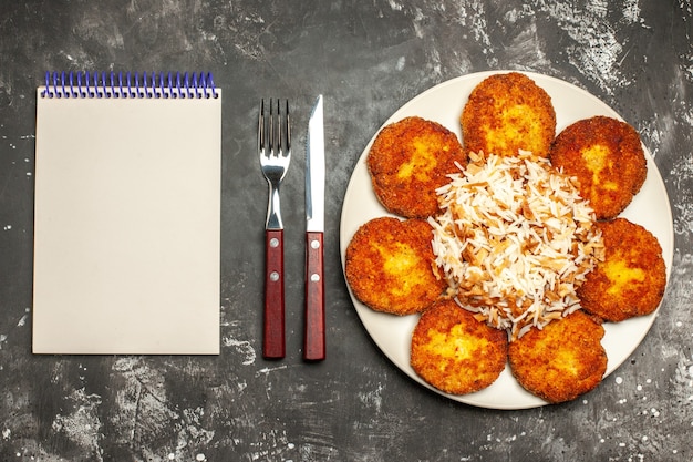 Draufsicht leckere gebratene schnitzel mit gekochtem reis auf dunklem oberflächenmahlzeitfotoschalenfleisch