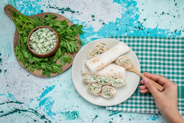 Draufsicht leckere Gemüsebrötchen ganz und in Scheiben geschnitten mit Gemüse und Salat auf dem blauen Schreibtisch Essen Mahlzeit Brötchen Gemüsesnack Farbe