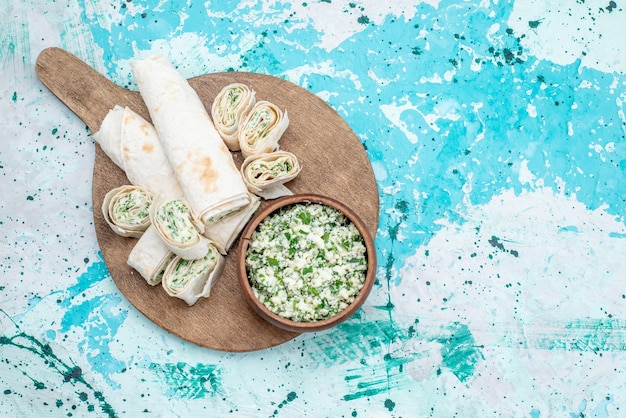 Kostenloses Foto draufsicht leckere gemüsebrötchen ganz und in scheiben geschnitten mit gemüsefüllung und kohlsalat auf dem hellblauen schreibtisch essen mahlzeit brötchen gemüse snack mittagessen